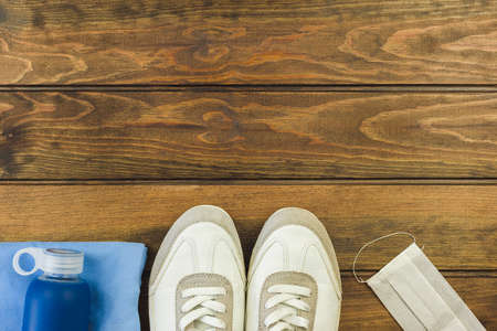 Flat lay of sports accessories with hygienic protective mask and on wood background ,be healthy, protection from coronavirus or COVID-19 during exercise concept. Space for text.の写真素材