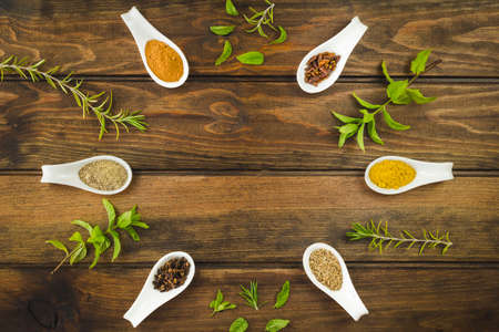 Various colorful herbs and spices on a wooden table. Fresh herbs and spices selection over old wood. Turmeric on dark vintage background with space for text.の写真素材
