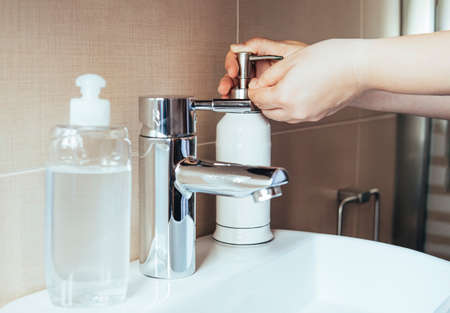 Young woman applying liquid soap to her hands.Hygiene concept, hand detail. Selective focus.