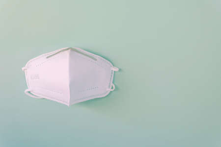 White medical mask isolated on green background. Face mask protection against pollution, virus, flu and coronavirus. Health care and surgical concept. Space for text. N95.の写真素材