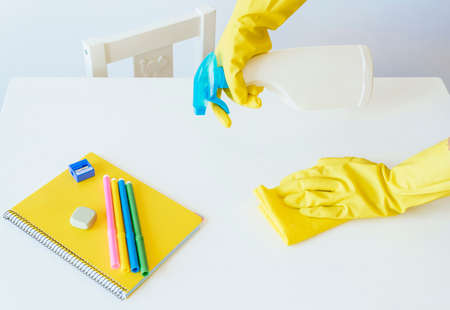 Teacher back at school after covid-19 quarantine and lockdown, disinfecting desks.の写真素材