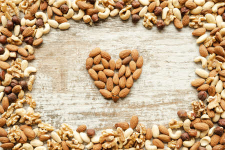 Nuts mix, healthy and beneficial food, vintage wooden background. Healthy concept. Top view. Almonds forming a heart.の写真素材