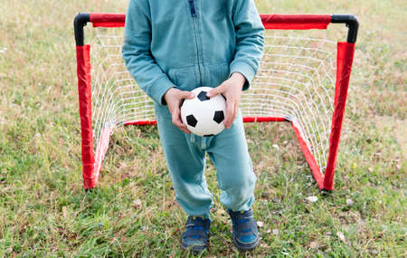 Young little kid enjoying happy playing football soccer at grass city park field