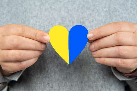 Woman holding a heart with the Ukrainian flag with both hands. Stop war Russia Ukraine.の写真素材