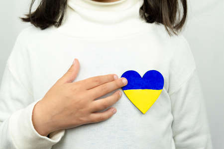 Girl holding a heart with the Ukrainian flag. Peace, stop war.の写真素材