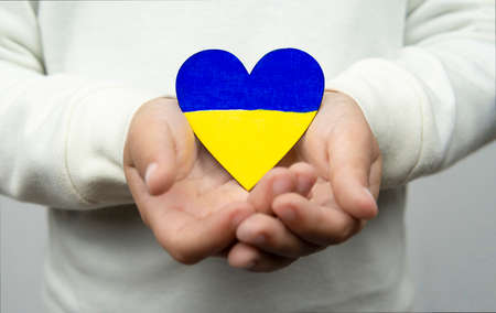 Girl holding a heart with the Ukrainian flag. Peace, stop war.の写真素材