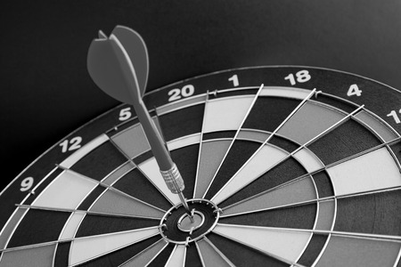Dart arrow hitting in the target center of dartboard (Black And White)の写真素材