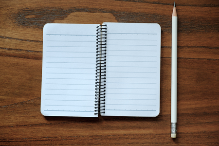 Blank notebook with pencil on brown wood table