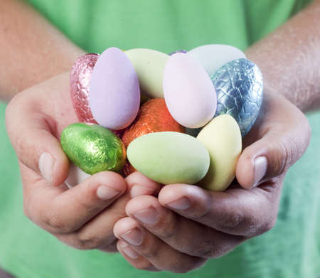 Male Caucasian hands holding out colourful Easter egg candy.