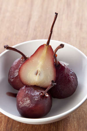 Pears poached in red wine in a white bowlの写真素材