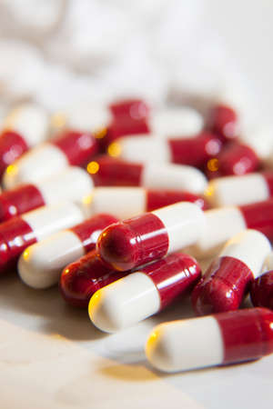 Red and white capsules on a white table topの写真素材