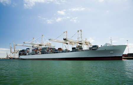 Cargo ship moored in commercial harbor in Cape Town, South Africa, being loaded up with containers.の写真素材