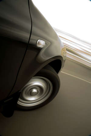 Black car turning sharply to its right, showing speed in tracking blur.の写真素材
