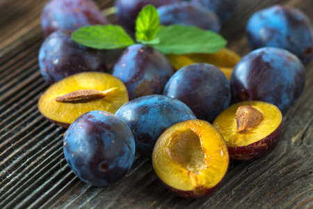 Plums in Bowl on Aged Wooden Tableの写真素材
