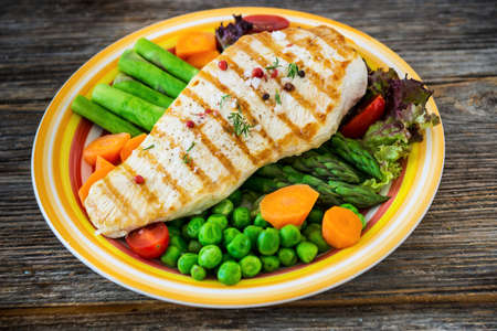 Grilled turkey fillet with vegetables on wooden backgroundの写真素材