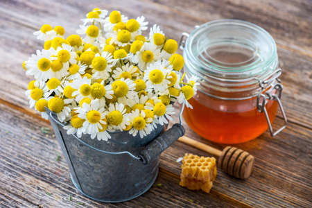 Chamomile flowers and honey on wooden backgroundの写真素材
