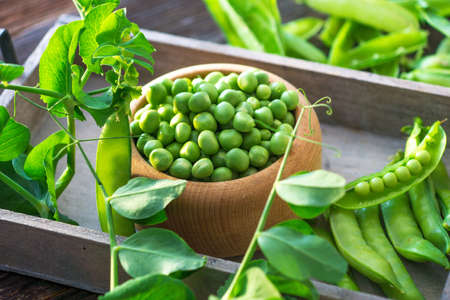 Bowl with fresh peas on a wooden background