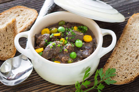 Chicken liver in  sauce with vegetable on wooden backgroundの写真素材