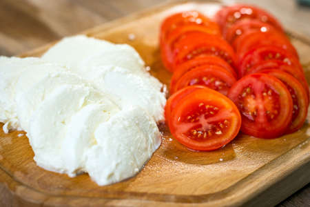 Sliced mozzarella an tomato on cuting boardの写真素材