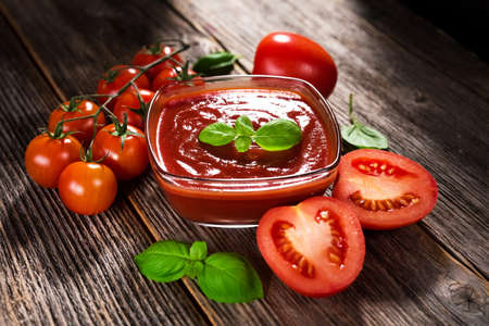 Tomato sauce and fresh tomatoes on rustic backgroundの写真素材