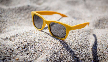 yellow sunglasses sun on the beach sandの写真素材