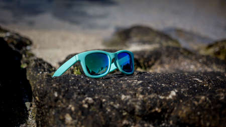 blue sunglasses sun on a rock on the beachの写真素材