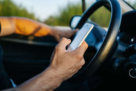 Man using phone with hand while driving a carの写真素材