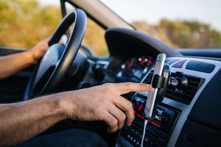 Man using phone with hand while driving a carの写真素材