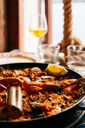 Paella on a table of a restaurant with a glass of beer next to a windowの写真素材