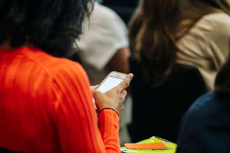 Detail of a woman's hands using a mobile phone or tablet at a congress