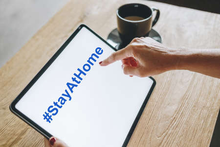 A digital tablet with hand, with the text Stay at home on the screenの写真素材