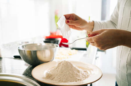 A woman prepares the ingredients to make a sponge cake in her home kitchenの写真素材