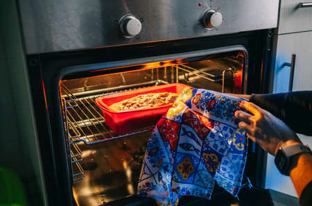 A woman puts a sponge cake in the oven to bake itの写真素材