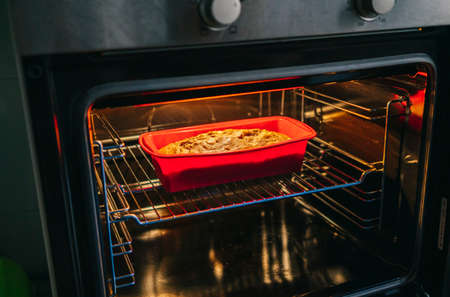 A woman puts a sponge cake in the oven to bake itの写真素材