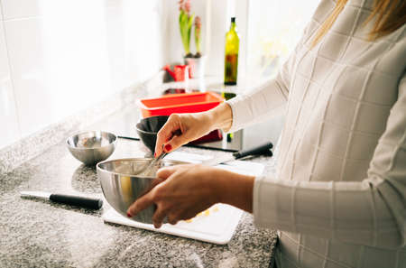 A woman prepares the ingredients to make a sponge cake in her home kitchenの写真素材