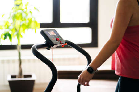 Beautiful caucasian blonde woman exercises on a treadmill in her living roomの写真素材