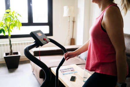Beautiful caucasian blonde woman exercises on a treadmill in her living room