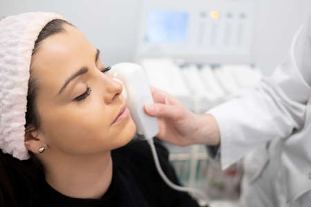 A beautiful girl doing facial care analyzing the skin of the face with a health and beauty device in...