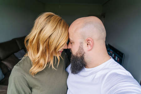 A couple of man and woman take a selfie photo with the mobile phone in the window of their houseの写真素材