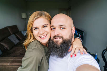 A couple of man and woman take a selfie photo with the mobile phone in the window of their house