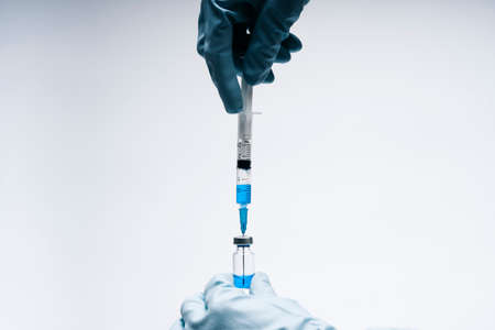 Hands of a doctor with a syringe and a vaccine. Blue latex gloves. Concept medicine and vaccine....