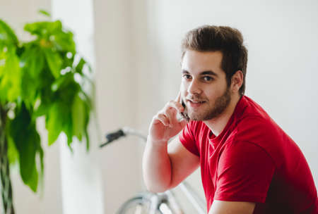 A boy in a red shirt talks on the phone in his living room. Stay at home concept.