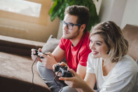 A couple on the couch in the living room at home playing video game console