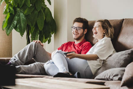 A young couple on the living room sofa relaxed watching TVの写真素材