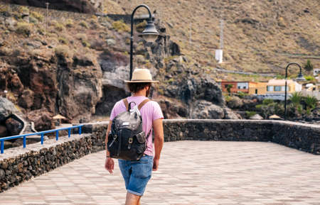A tourist man with hat and backpack through a village on the coast of El Hierro, Canary Islandsの写真素材