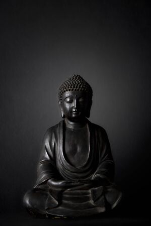black buddha meditating statue with black backgroundの写真素材