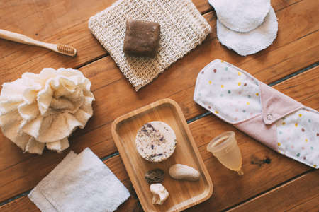 Natural and ecological women's personal hygiene products in natural wood base. solid natural handmade shampoo. Bamboo toothbrush. Reusable cotton make-up removal wipes. Reusable cloth pad. Reusable cloth sponge. Menstrual cup. Zero waste concept. Ecological concept. Environmental sustainability conceptの写真素材