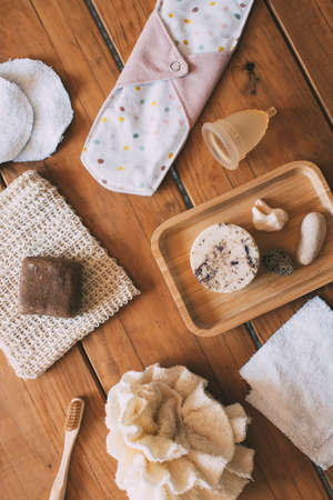 Natural and ecological women's personal hygiene products in natural wood base. solid natural handmade shampoo. Bamboo toothbrush. Reusable cotton make-up removal wipes. Reusable cloth pad. Reusable cloth sponge. Menstrual cup. Zero waste concept. Ecological concept. Environmental sustainability conceptの写真素材