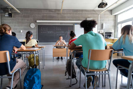 Multiracial group of teen high school students in classroom with mature white male teacher. Copy space. Education concept.の写真素材