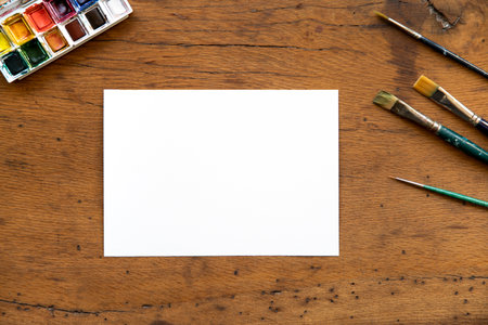 Flat lay of blank sheet of paper, watercolor palette and paint brushes on wood table. Art concept. Mockup. Copyspace. Creativity concept.の写真素材